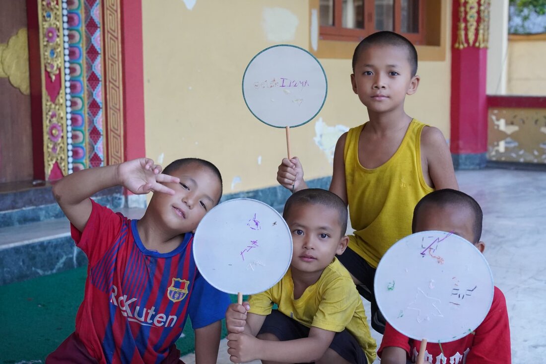 Children holding round fans decorated with their embroidery.