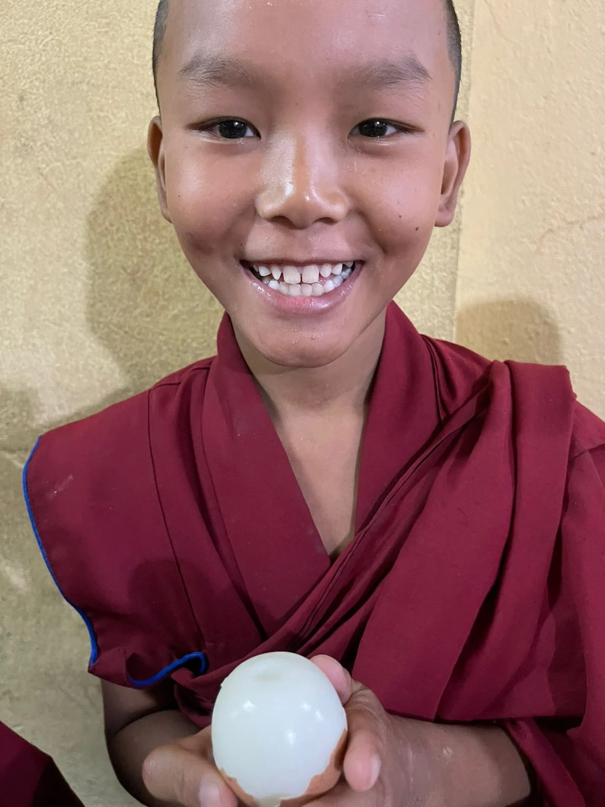 A smiling child holding a peeled boiled egg.