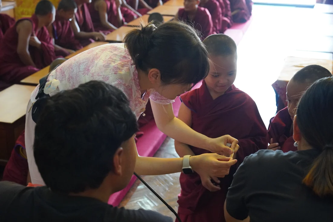 The facilitator demonstrating how to apply a bandage to a child during an everyday hygiene lesson, with other children watching.