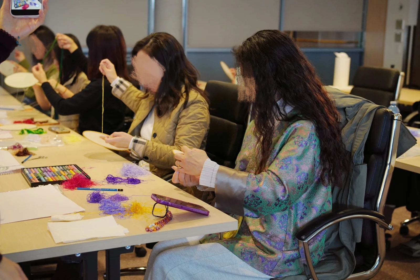 Participants working on round-fan embroidery together at a community mindful art workshop.