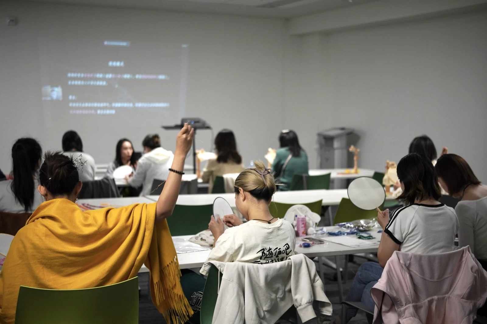 Participants practising embroidery on round fabric fans during a mindful art workshop.